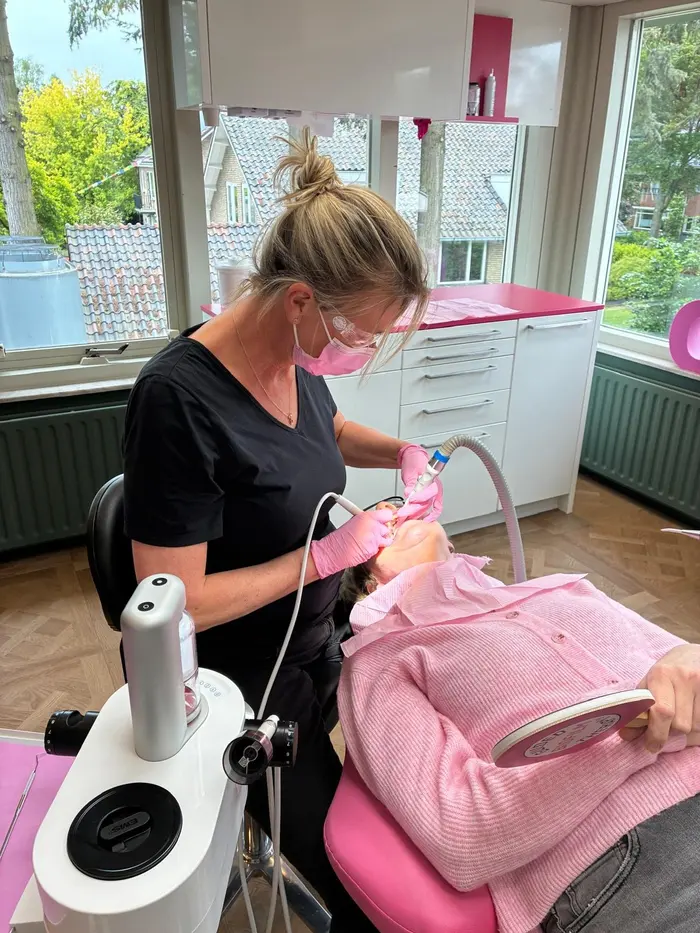 Marjon Ooteman aan het werk in de praktijk, met loepbril en mondmasker